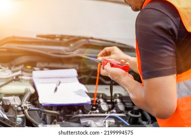 Closeup And Crop Motor Vehicle Mechanic Checking Engine Oil To Record The Repair History With Sun And Lens Flare Background.