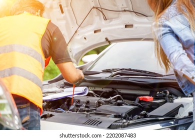 Closeup And Crop Motor Vehicle Mechanic Checking Engine Oil To Record The Repair History With Sun And Lens Flare Background.