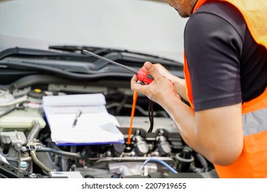 Closeup And Crop Motor Vehicle Mechanic Checking Engine Oil To Record The Repair History On Car Engine Background.