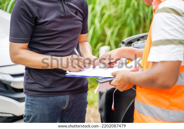 Closeup and crop traffic accident and\
insurance agent working on report form with car accident claim\
process on blurred\
background.