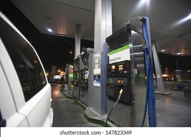 Closeup Of Cropped Car At Gas Station With View Of Fuel Pumps And Natural Gas At Night