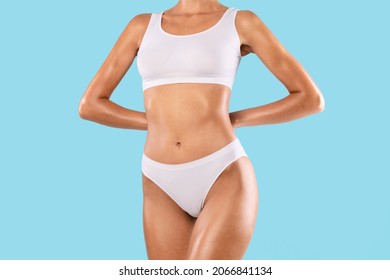 Closeup Cropped Frontal View Of Slim Lady With Perfect Body Shape And Flat Tummy Posing Isolated On Blue Studio Background, Woman Wearing White Lingerie Top Bra And Panties. Fitness, Diet Concept