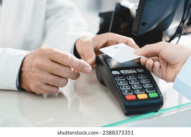 Closeup cropped image of e-commerce e-banking cashless wireless payment with credit card at drugstore pharmacy at cash point desk, buying medicines, drugs, pills - Powered by Shutterstock