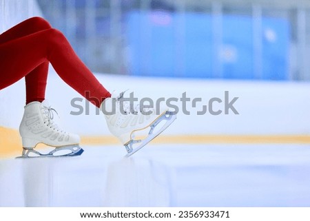 Close-up cropped image of female legs in red leggings and white skates on ice skate arena. Training and skating. Concept of professional sport, competition, sport school, health, hobby, ad