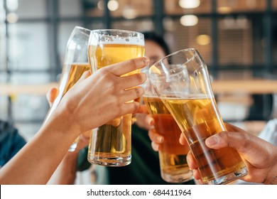 Close-up cropped image of friends clinking with beer in cafe - Powered by Shutterstock