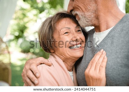 Closeup cropped image of love and care. Affectionate old senior couple family spouses grandparents kissing hugging embracing outdoors in the garden. Physical touch - love language