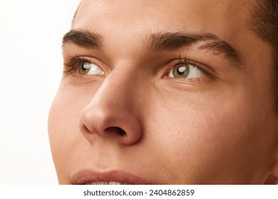 Close-up cropped image of male face, eyes, nose and eyebrows against white studio background. Concept of male beauty, skin care, spa, cosmetology, men's health
