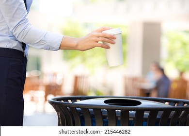 Closeup Cropped Image Woman's Hand Throwing Empty Paper Coffee Cup In Recycling Bin, Isolated Outside, Trees Background. Recycling, Eco Friendly Approach Concept. Keep Streets, City, Earth Clean