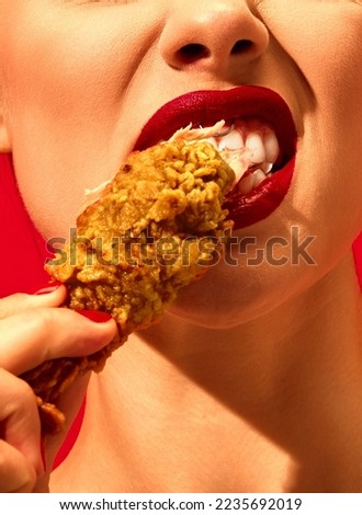 Close-up cropped image of young woman eating fried chicken, nuggets over vivid red background. Spicy taste. Food pop art photography. Complementary colors. Copy space for ad, text