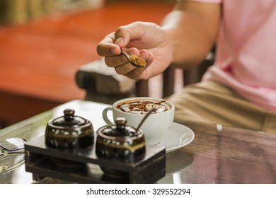 Closeup Of A Cropped Man Pouring Sugar Into Coffee Cup