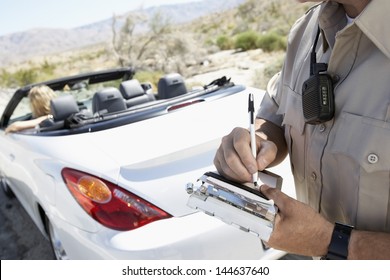 Closeup Of A Cropped Police Officer Writing Traffic Ticket To Woman Sitting In Car