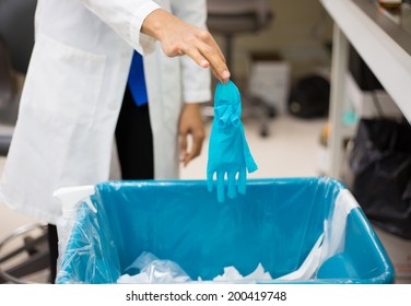 Closeup Cropped Portrait, Healthcare Professional Throwing Away Blue Disposable Latex Gloves In Trash.  Infection Control Protocol. Isolated Lab Background