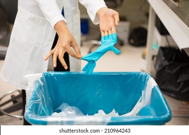 Closeup Cropped Portrait, Healthcare Professional Throwing Away Blue Disposable Latex Gloves In Trash. Infection Control Protocol. Isolated Lab Background