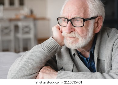 Closeup cropped portrait of lonely missing old people, senior man elderly grandfather sitting on the sofa, feeling pain, sick, ill, nostalgy, fraud, bankruptcy at home alone, needing help. - Shutterstock ID 2115835481