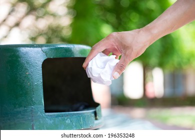 Closeup Cropped Portrait Of Someone Tossing Crumpled Piece Of Paper In Trash Can, Isolated Outdoors Green Trees Background