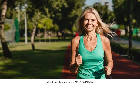 Closeup cropped shot of a female caucasian mature woman running jogging outdoors looking at camera. Slimming workout training - Powered by Shutterstock