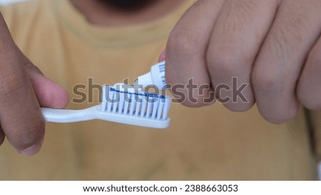 Closeup cropped view of a hands squeezing toothpaste onto a toothbrush