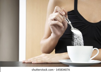 Closeup of a cropped woman pouring sugar into tea cup - Powered by Shutterstock