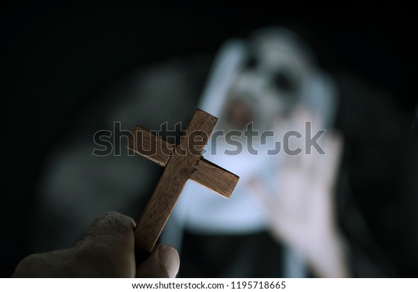 closeup a cross\
in the hand of a man and a frightening evil nun, wearing a typical\
black and white habit,\
screaming