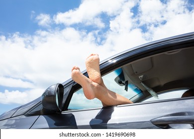 Close-up Of Crossed Woman's Leg Out Of Car Window At Beach