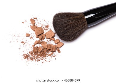 Close-up of crushed bronzing powder with makeup brush on white background. Bronzer to create a tanned look or light contouring on the face