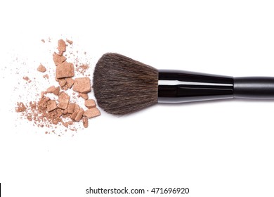 Close-up of crushed bronzing powder with makeup brush on white background. Bronzer to create a tanned look or light contouring on the face
