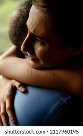 Close-up Of A Crying Girl Hugged By Her Father. Tears On The Woman's Face. A Strong Hug Of Support