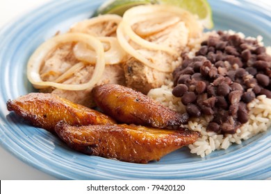 Closeup Of Cuban Dinner With Focus On Fried Sweet Plantains.  Marinated Roast Pork With Black Beans And Rice Complete The Meal.