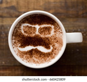 Closeup Of A Cup Of Cappuccino With A Pair Of Eyeglasses And A Moustache Drawn With Cocoa Powder On Its Foam