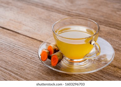 Close-up Cup Glass Of Hot Turmeric Tea ( Curcumin, Curcuma Longa Linn ) Isolated On Wood Table Background. Healthy Drinks And Antioxidant Food Concept.