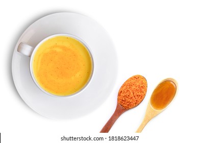 Closeup cup of golden milk (turmeric latte tea) with tumeric powder and pure honey in wooden spoon isolated on white background. Top view. Flat lay.
