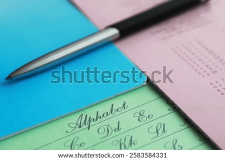 Close-up of Cursive Alphabet Practice Sheets with Pen on Colorful Paper Background
