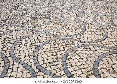 Closeup of curvy, undulating patterns in stone mosaics of basalt and limestone rock in Portugal
