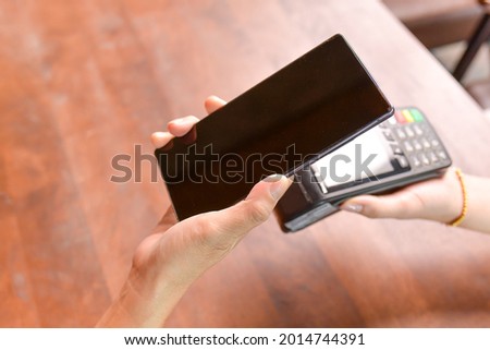 Closeup of a customer using her smartphone and nfs technology to payment