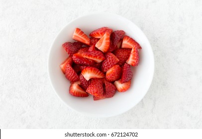 Closeup Of Cut Strawberries In A White Porcelain Bowl Isolated On White Marble Background With Lots Of Copy Space. 