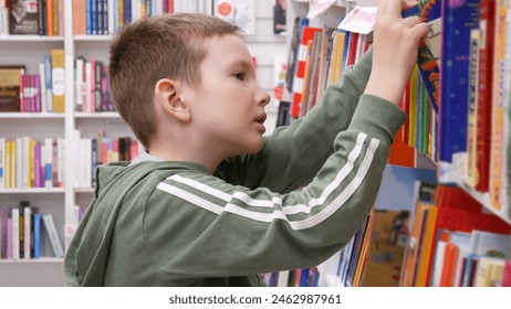 Close-up of a cute boy choosing a book in a book shop or library - Powered by Shutterstock