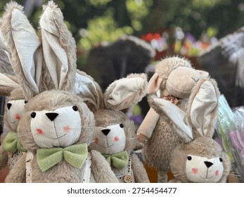 Close-up of cute plush Easter bunny toys displayed together as part of a spring holiday decoration. The soft stuffed rabbits with long ears and gentle pastel colors create a warm and playful seasonal atmosphere associated with Easter celebrations and springtime traditions. These decorative bunny toys are often used as festive ornaments, gifts for children, and elements of seasonal home decor. The blurred natural background and soft lighting enhance the cozy and cheerful mood, making the image suitable for greeting cards, holiday promotions, family events, and spring marketing campaigns. This composition with adorable stuffed animals works well for seasonal advertising, social media posts, greeting cards, children's products, and festive design projects.