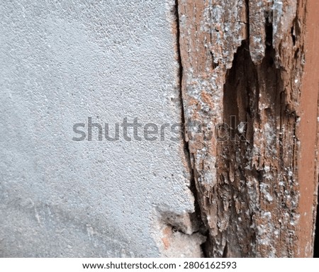 Close-up of a damaged wooden structural element with deep longitudinal cracks beside a rough concrete wall. The image highlights weathering, aging materials, and structural deterioration, making it suitable for construction, civil engineering, building inspection, renovation, maintenance, and property damage concepts.
