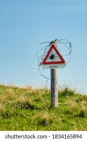 Close-up: Danger: Beware Of Ticks. Triangle Warning Sign On A Meadow With The Word 