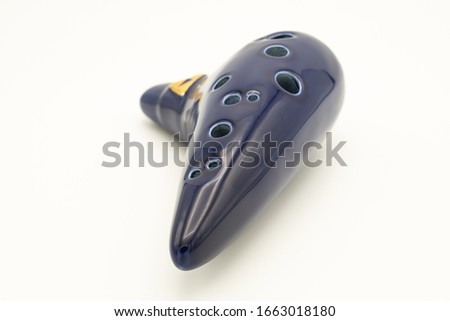 Closeup of a dark blue ocarina in front of white background