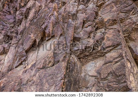Closeup of dark dged shabby cliff cracks. Gray stone rock texture of mountains. Concept of geology and mountaineering