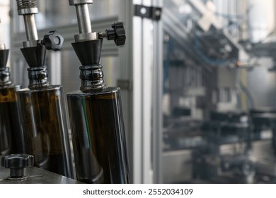 Close-up of dark glass olive oil bottles with metal dispenser pumps in production line. Manufacturing quality control and industrial equipment detail with shallow depth of field. - Powered by Shutterstock