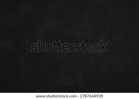 A close-up of a dark, textured surface with subtle reflective particles.