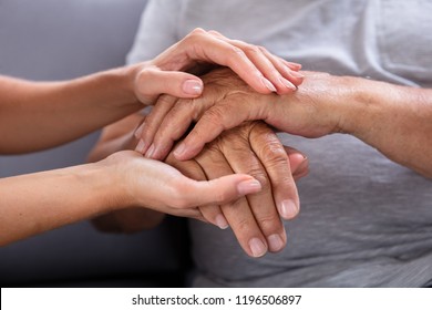 Close-up Of A Daughter Holding Her Elderly Father's Hand