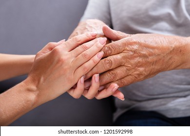 Close-up Of A Daughter Holding Her Elderly Father's Hand