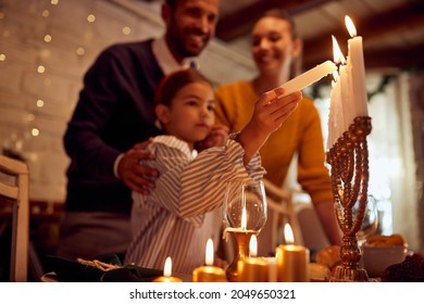 Close-up of daughter lighting the menorah during family diner on Hanukkah.