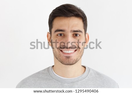Close-up daylight portrait of young smiling handsome man isolated on gray background