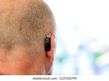 Close-up Deafness Caucasian Middle Age Man  Wearing Digital Hearing Aid Or Hearing Amplifier To Assist His Hearing.