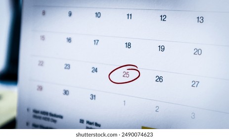 A close-up of December 25, 2024, on an office calendar, circled in red marker to indicate a holiday, with a blurred office workspace in the background. - Powered by Shutterstock