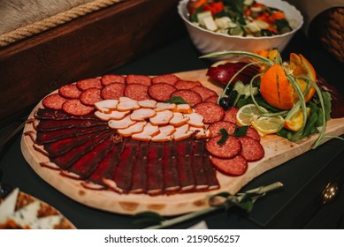 A Closeup Of Decorated Cured Meat Platter Next To Salad Bowl On The Table